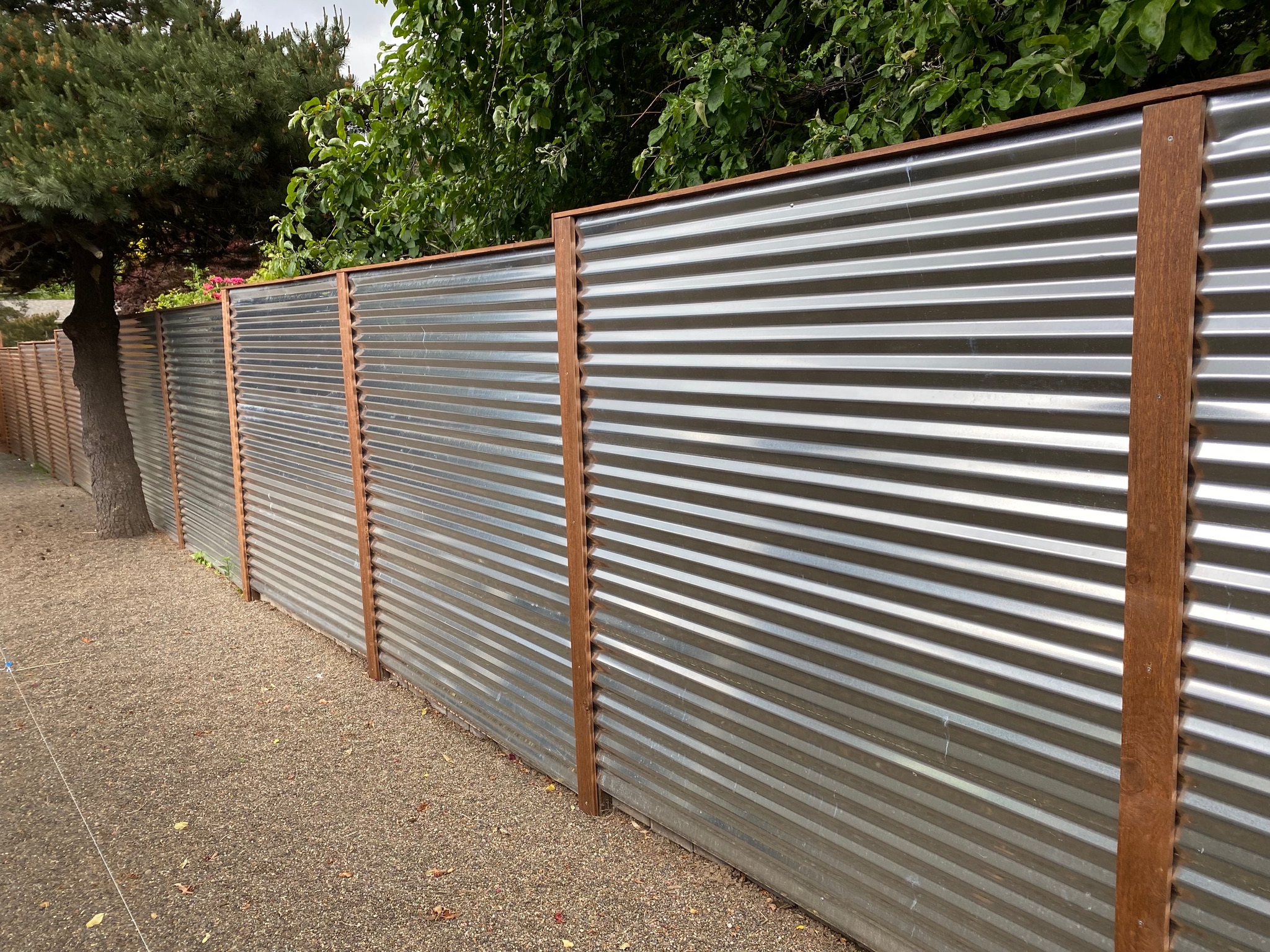 Finished privacy fence combining corrugated metal panels with cedar framing