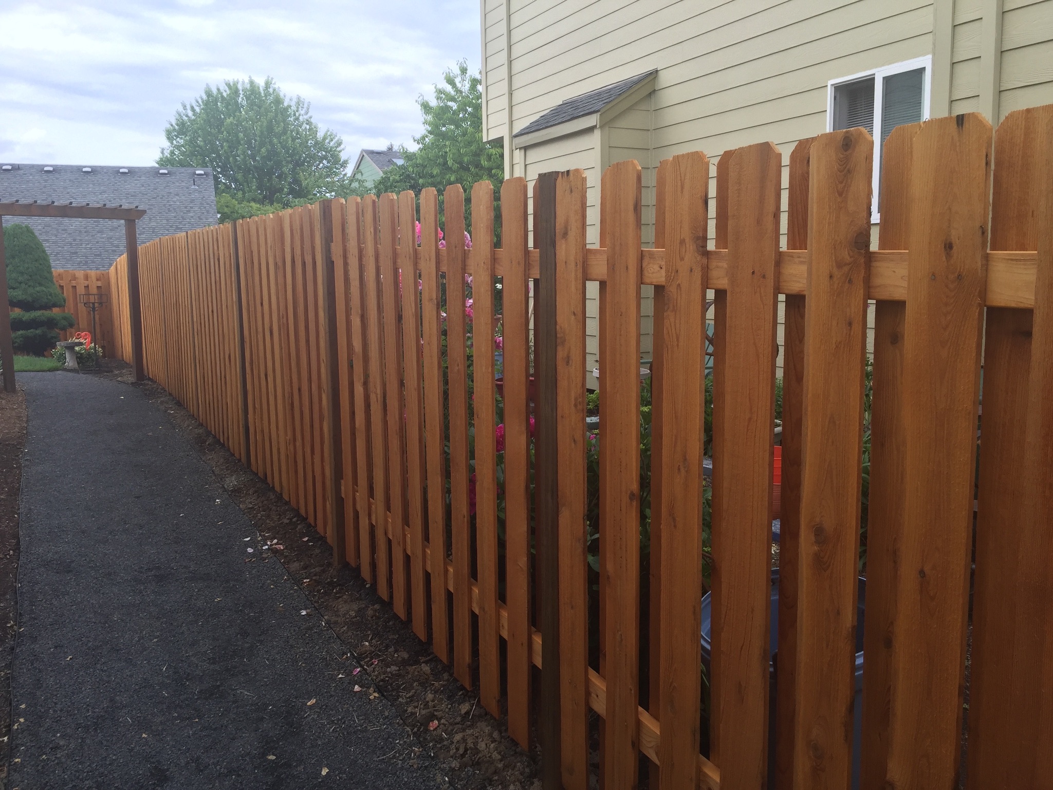 Finished dogeared cedar privacy fence running beside a home