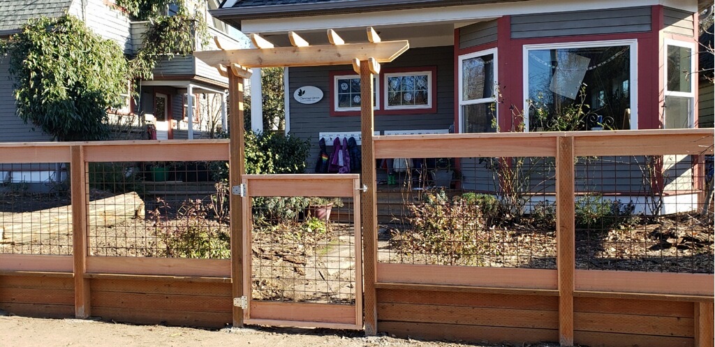 Finished cedar and hogwire gate beneath a simple arbor