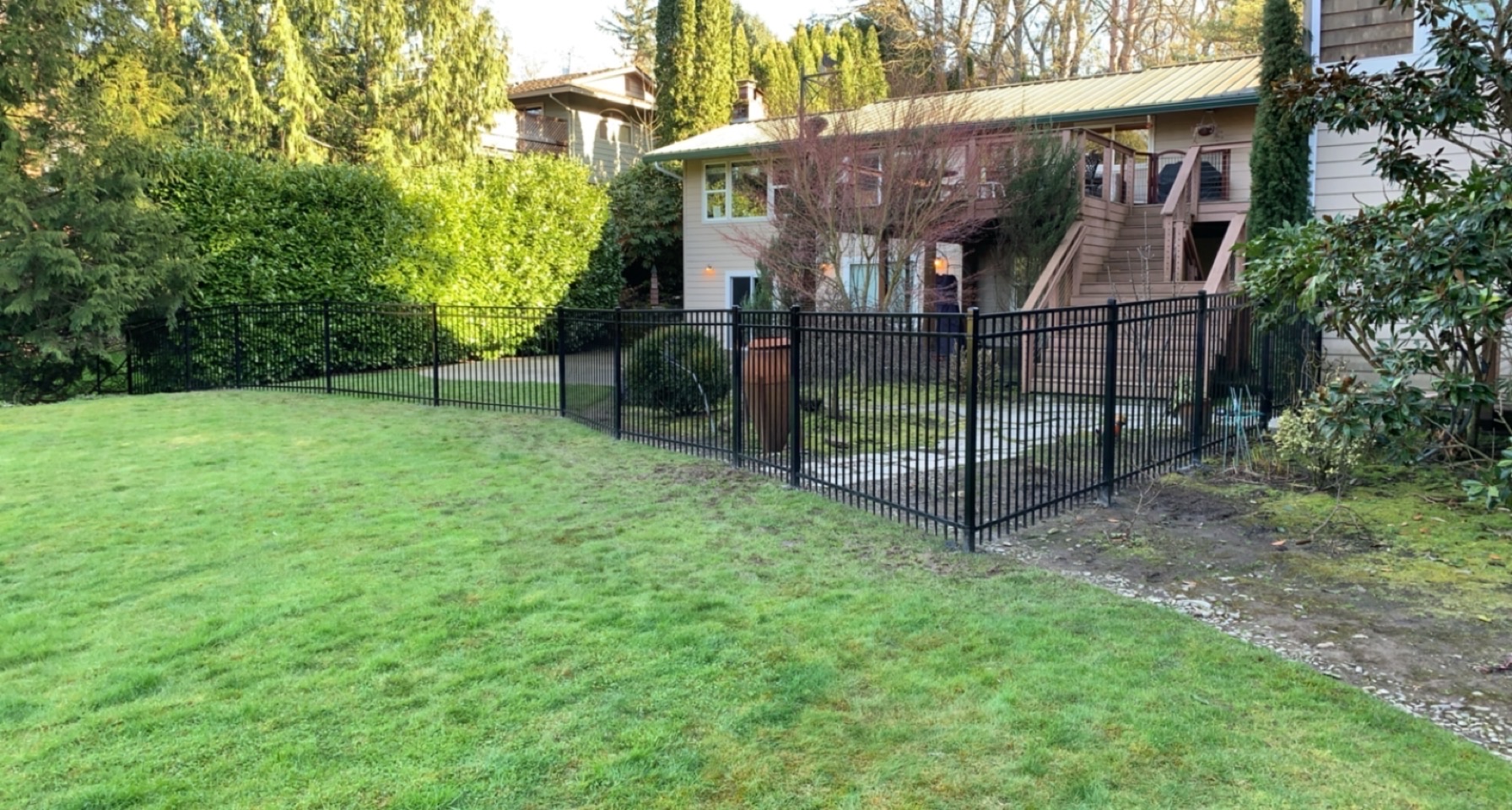Finished black ornamental steel fence around a backyard