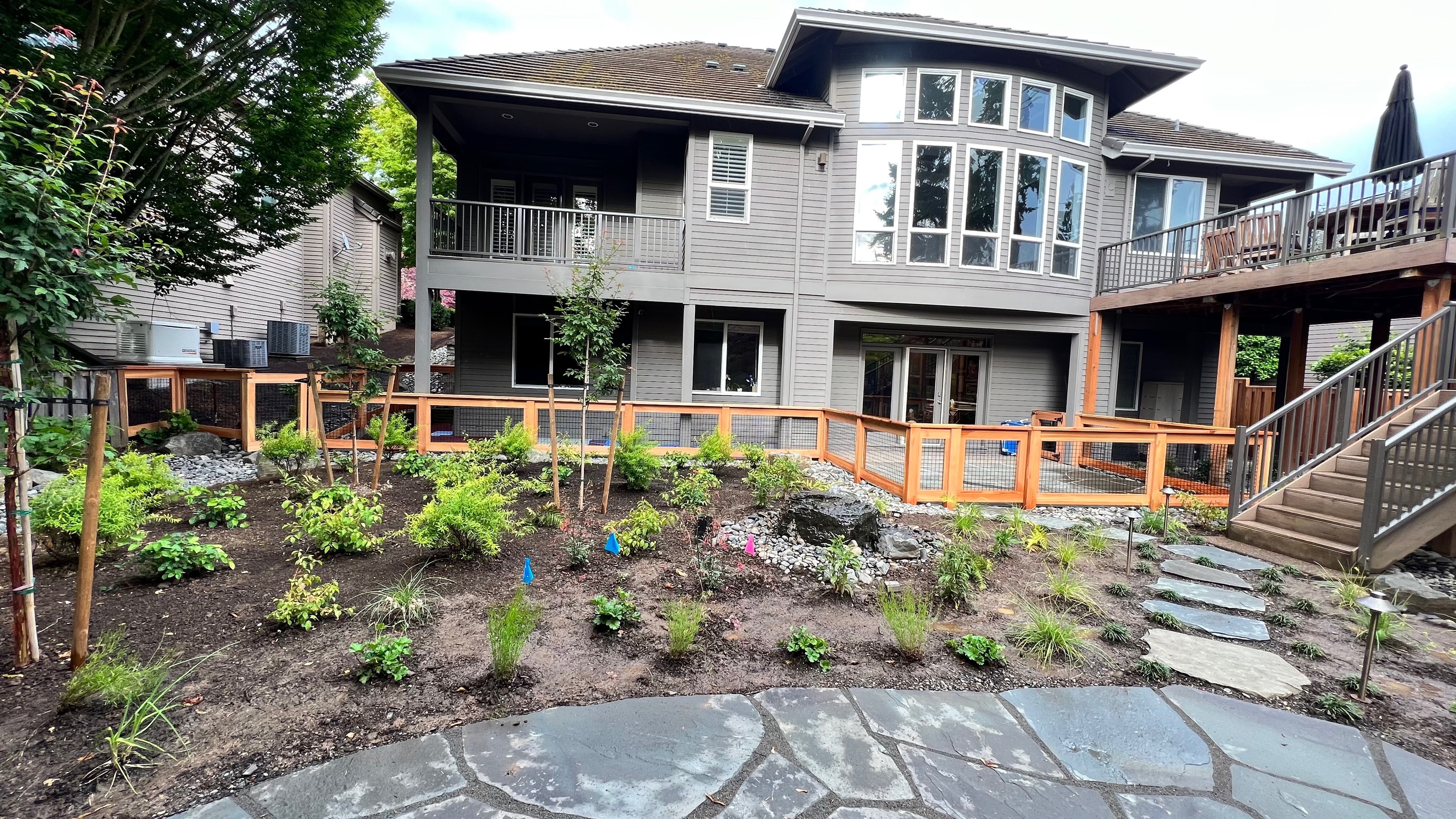 Completed cedar and hogwire fence around a landscaped backyard