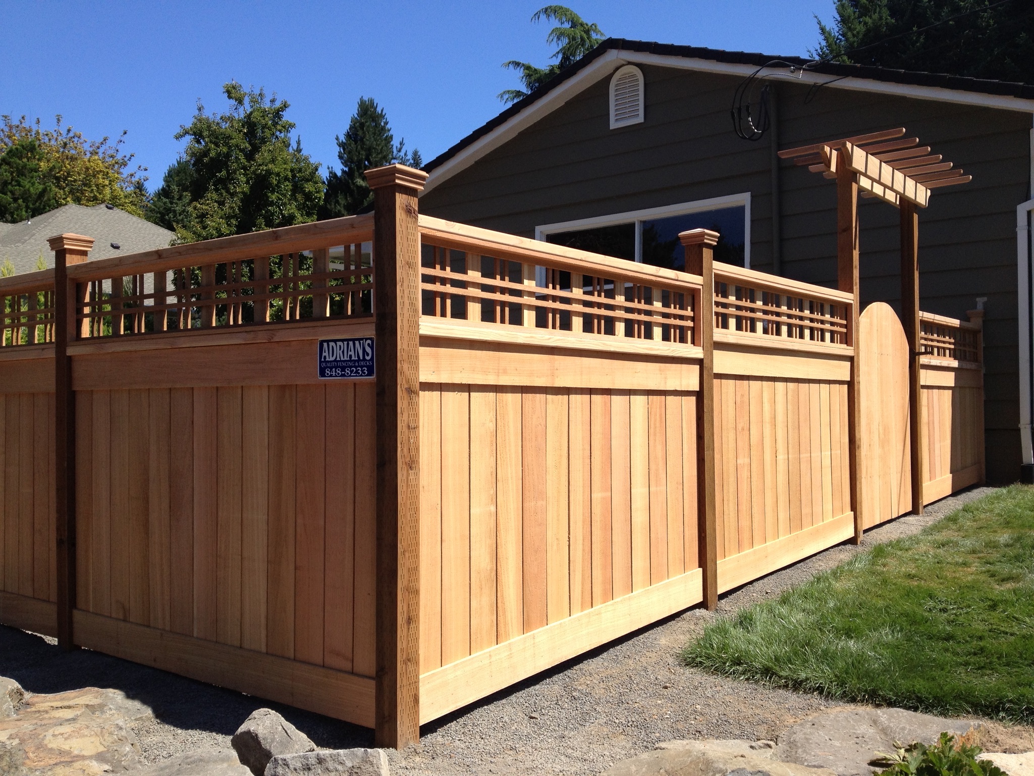 A completed cedar privacy fence with lattice detailing and a custom gate